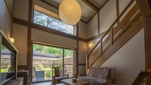 A spacious room with a large sliding glass door leading to a balcony, wooden furniture, and a traditional Japanese lantern. - Shionoyu Onsen Rengetsu (Nasushiobara)