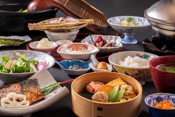 A variety of traditional Japanese dishes arranged on a table, including rice, vegetables, and seafood.