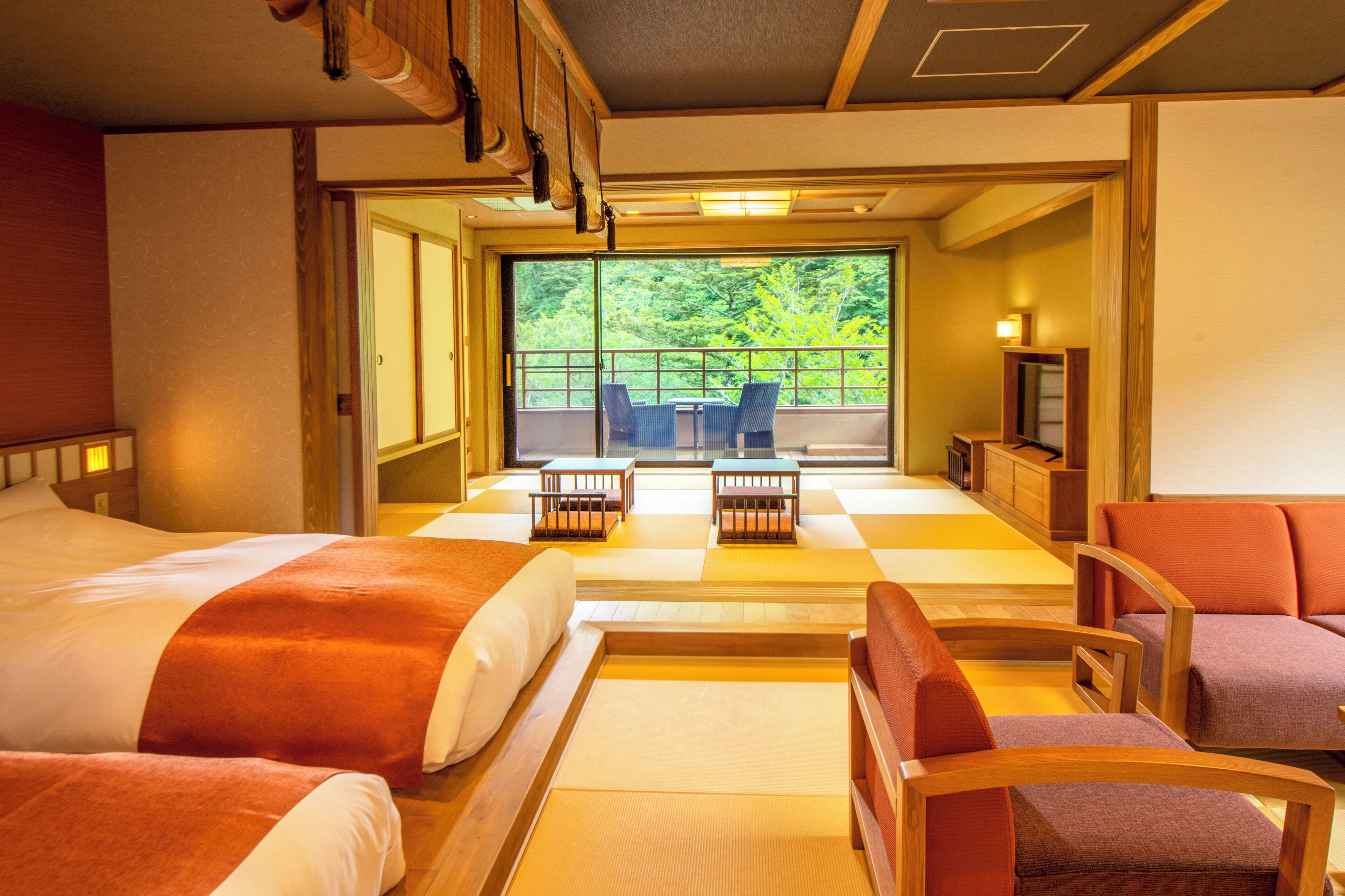 Habitación de hotel con dos camas, un balcón con mesa y sillas, y un televisor.