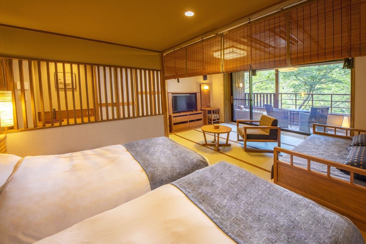 A hotel room with two beds, a TV, a small table, and a sofa.