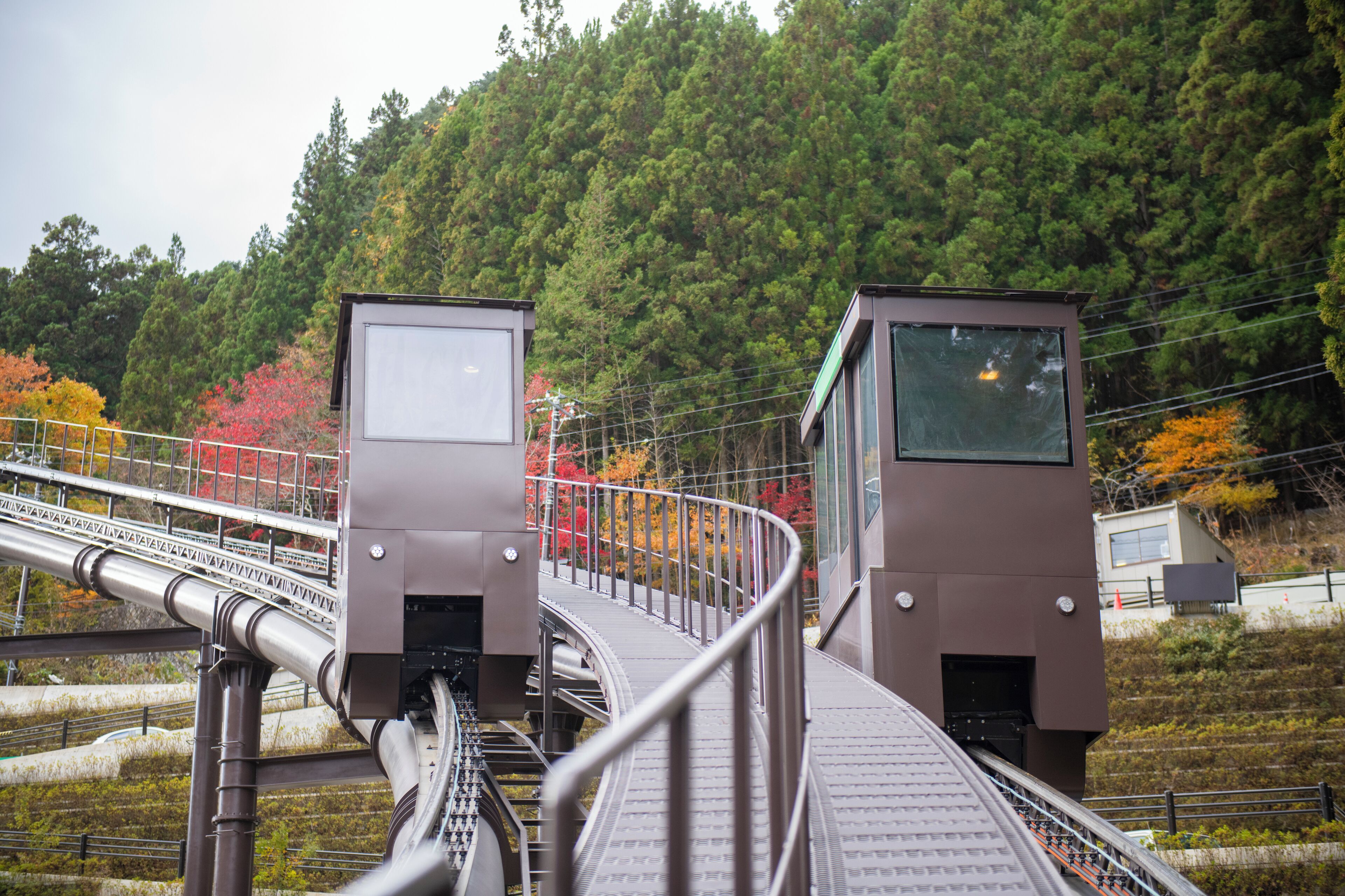 A train station platform with a curved track and two control boxes.