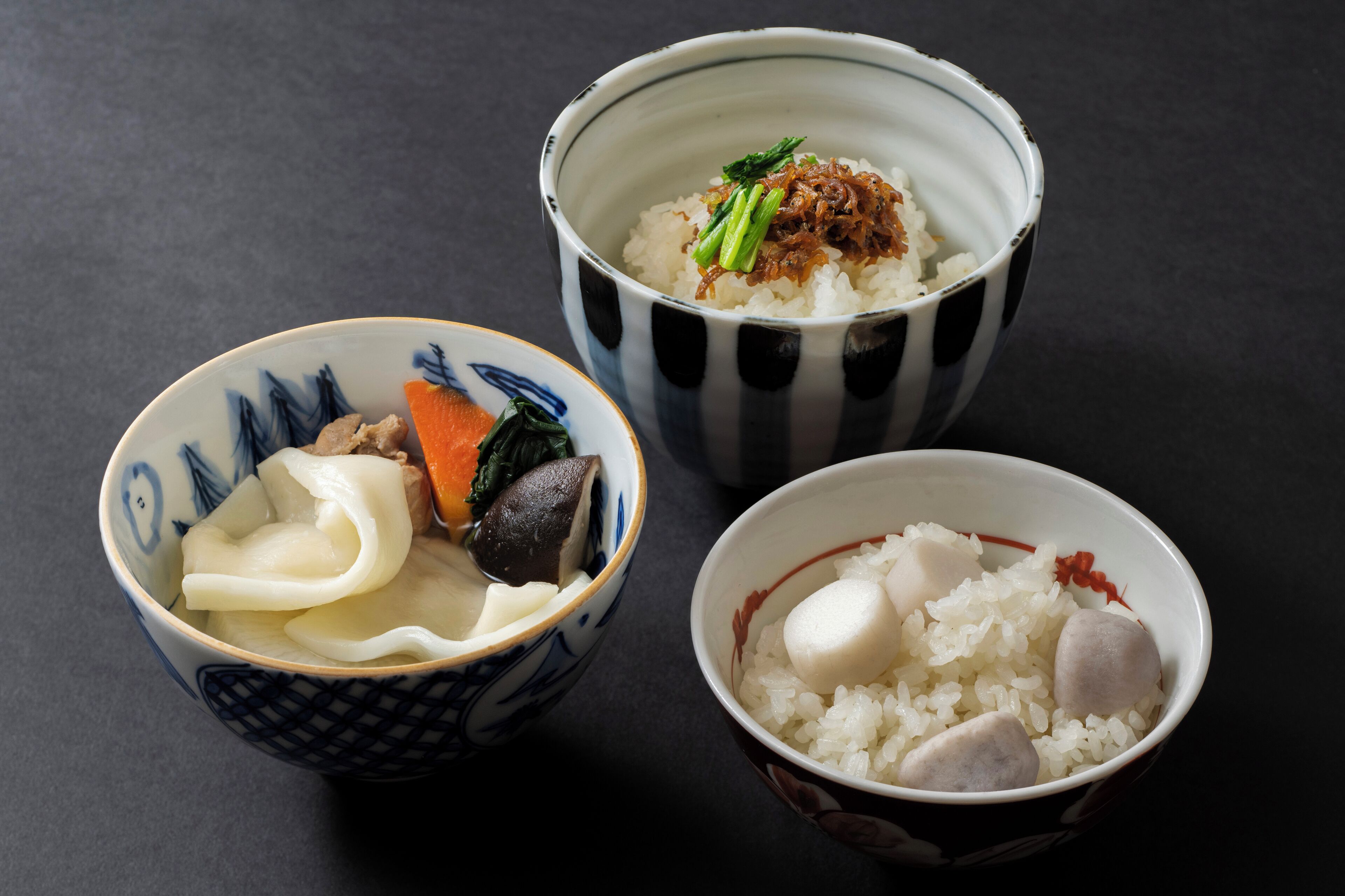 Three bowls of Japanese food with rice, vegetables, and fishcakes.
