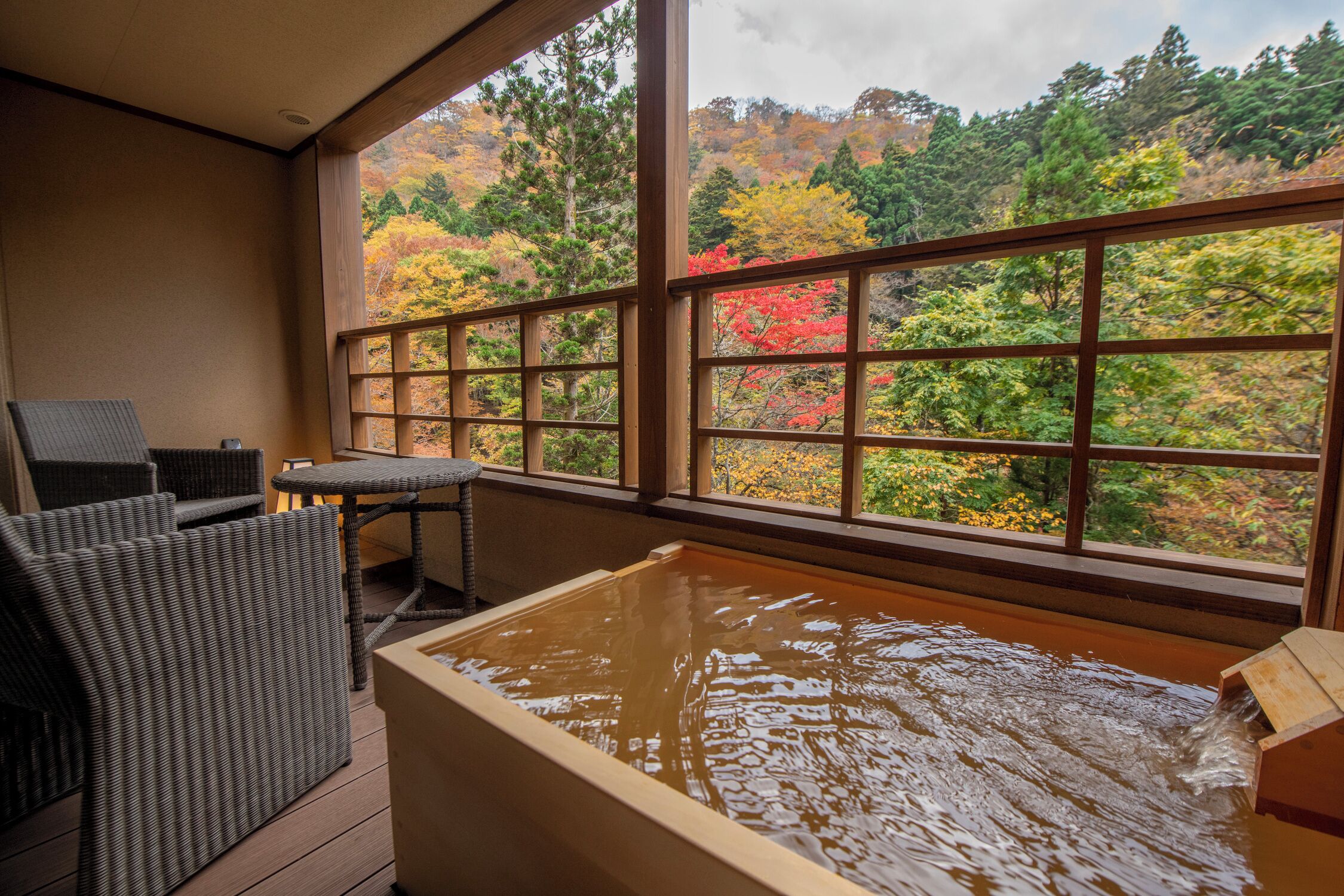 Ein Badebereich mit Thermalquellen und Blick auf Herbstbäume durch große Fenster.