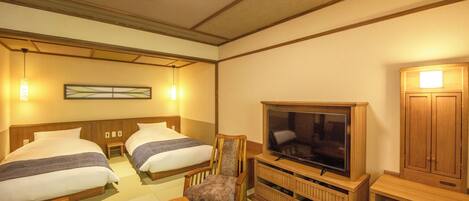 A hotel room with two beds, a television, a wooden cabinet, and a small table.
