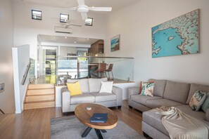 A modern living room with a sofa, coffee table, and a view of the kitchen and dining area.