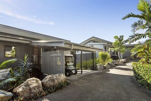 Une maison moderne dotée d’une allée couverte, de gros rochers et de plantes tropicales.
