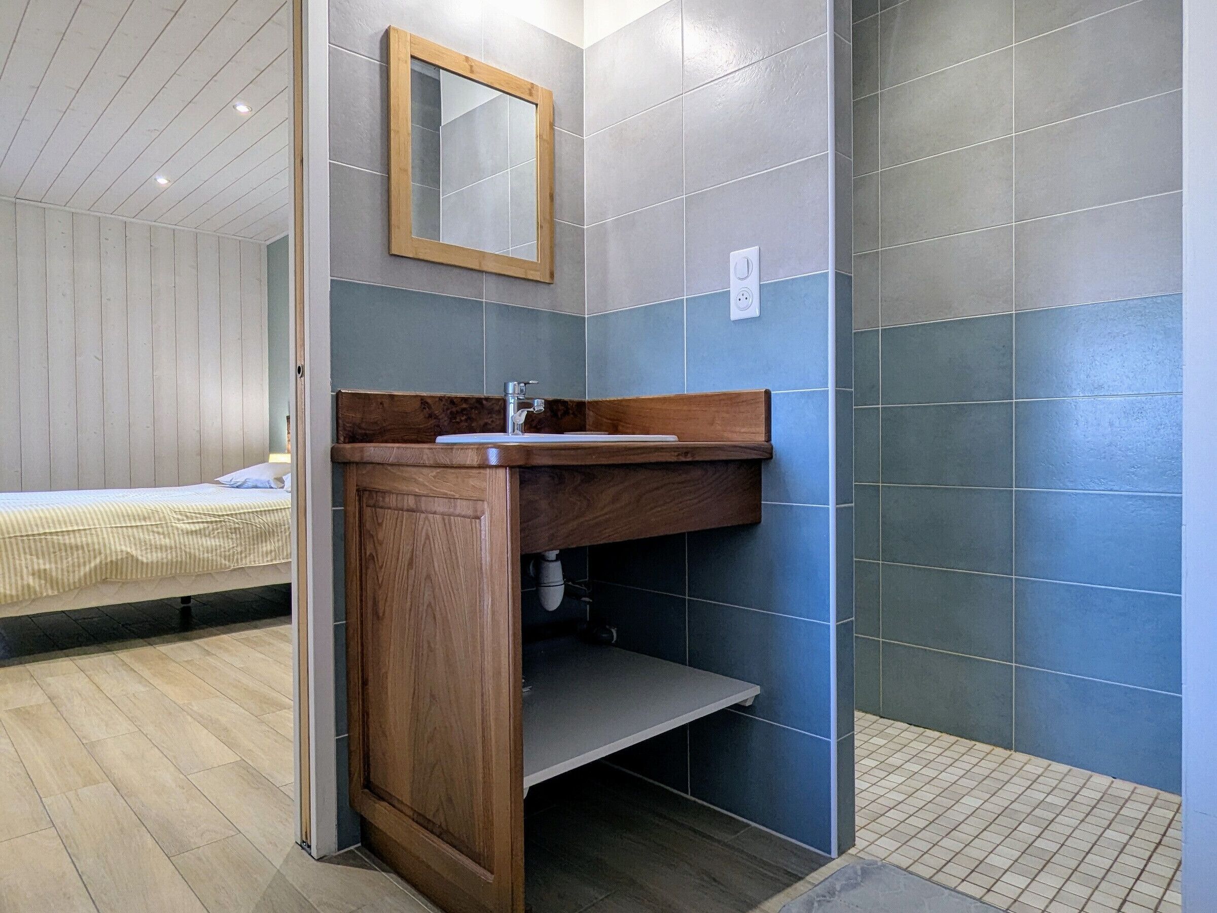 A bathroom with a wooden vanity, a mirror, and a sink.