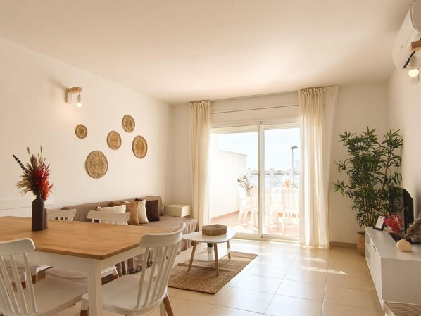 A modern living room with a dining area, a sofa set, a coffee table, and a large window with curtains.