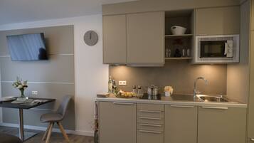 A modern kitchen with a microwave, sink, and cabinets. There is a dining table with chairs and a vase of flowers.