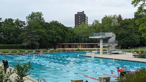 A swimming pool with multiple lanes, a lifeguard tower, and a surrounding park area with trees. - Evi's Home Hotel & Apartments (Bern)