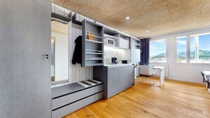 A modern kitchen with built-in appliances, a dining area, and a view of the city. - Evi's Home Hotel & Apartments (Bern)