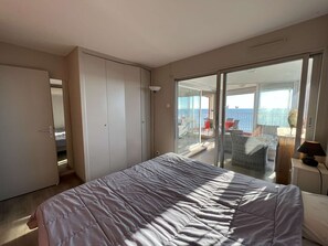 A bedroom with a bed, a sliding glass door leading to a balcony with outdoor furniture, and a wardrobe. - Beautiful 2-BR, A/C, Parking, Near Beach and Shops (Cap d'Agde)