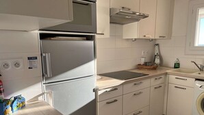 A modern kitchen with a built-in refrigerator, a sink, a washing machine, and a countertop with a basket.