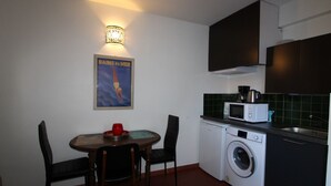 Una cocina compacta con lavadora, microondas y un cartel en la pared.