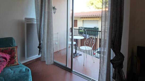 Una habitación con puerta de vidrio corrediza que da a un patio exterior con mesa y sillas.