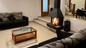 A living room with a fireplace, a sofa, a coffee table, and a staircase leading to another room. - Coastal Villa with Private Pool, Steps from Beach, 4 Bedrooms, BBQ, Wi-Fi, Family-Friendly (L'Ametlla de Mar)
