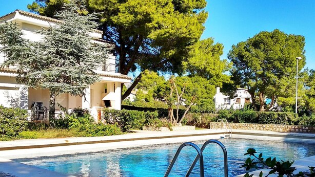 A swimming pool with a clear blue water, surrounded by greenery and buildings. - Coastal Villa with Private Pool, Steps from Beach, 4 Bedrooms, BBQ, Wi-Fi, Family-Friendly (L'Ametlla de Mar)