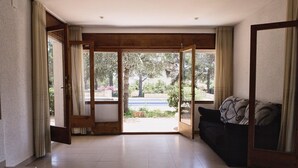 A spacious living room with a large sliding glass door leading to a garden. - Coastal Villa with Private Pool, Steps from Beach, 4 Bedrooms, BBQ, Wi-Fi, Family-Friendly (L'Ametlla de Mar)