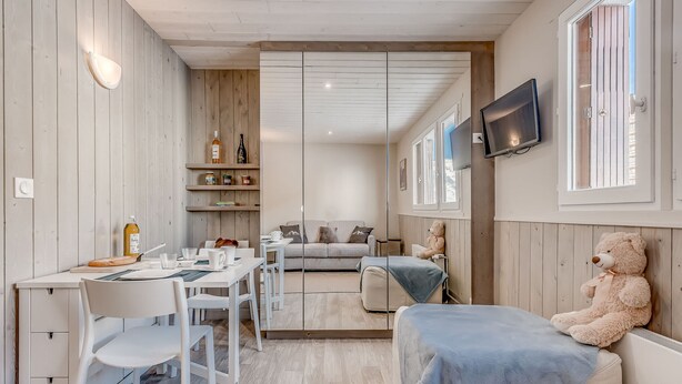 A modern, well-lit room with a dining area, a sofa, and a large teddy bear. - PREMIUM Studio in Tignes, 2 people, WIFI included (Tignes)