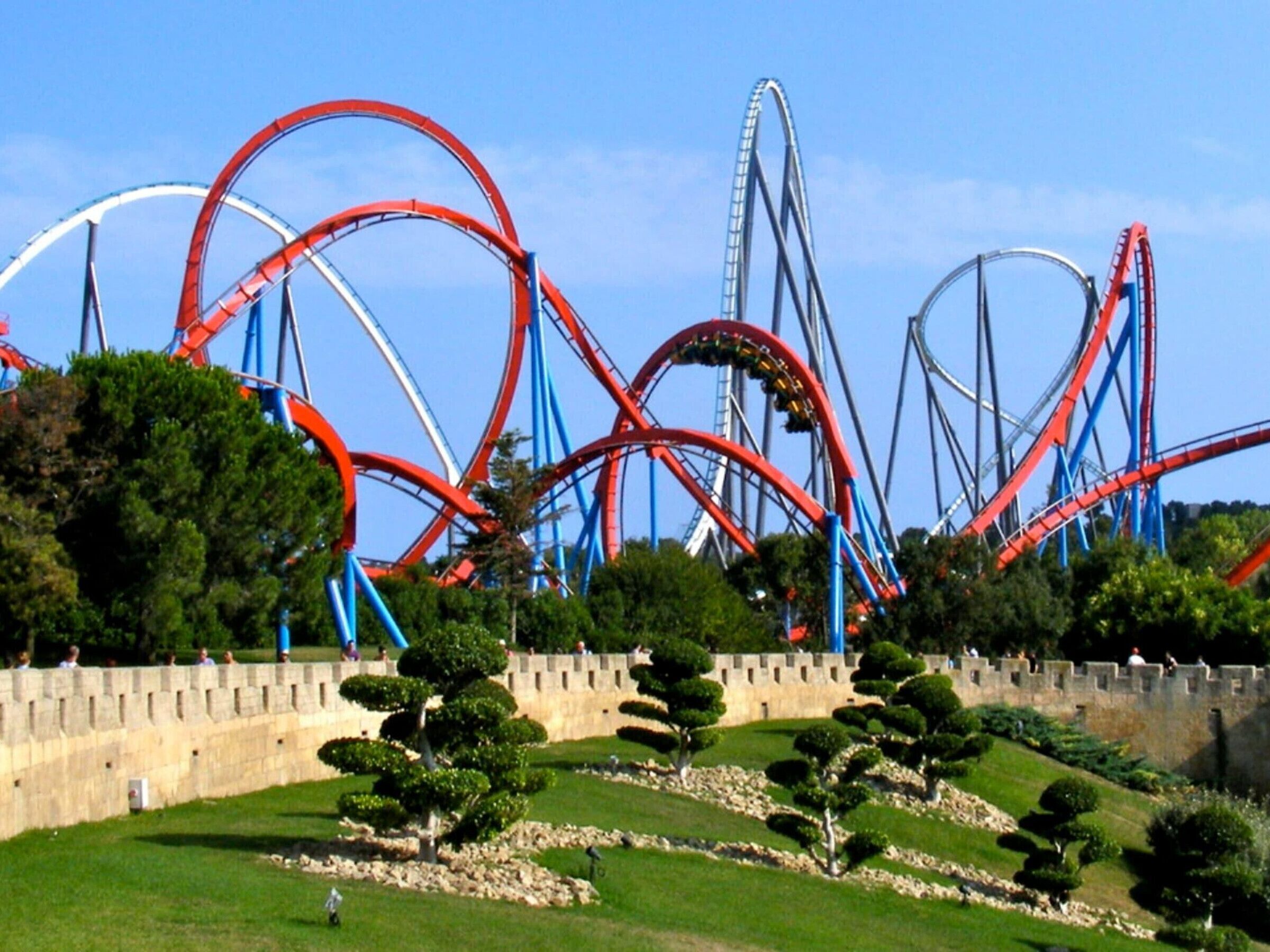 Een pretpark met meerdere achtbanen en een kasteelachtige structuur op de achtergrond.