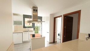 A modern kitchen with a built-in oven, a sink, and a window overlooking a garden. - Villa with Private Pool, 100m from Sea, Spacious Garden, Near Calafat in Costa Dorada (L'Ametlla de Mar)