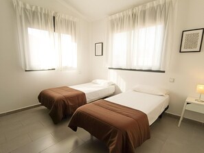 Una habitación con dos camas individuales, una mesita de noche con lámpara y un cuadro en la pared.