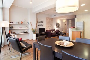 A modern living room with a dining area, featuring a large table, comfortable seating, and a fireplace.