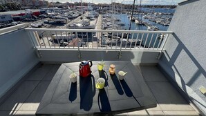 A balcony with a table, chairs, and a view of a marina with boats. - 1BR with AC, Pool, Private Garage (Cap d'Agde)