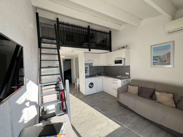 Um espaço compacto com cozinha compacta, um sofá e uma escada que leva a um andar superior.