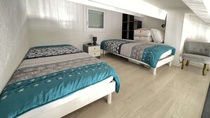 A bedroom with two beds, a small bedside table, a chair, and a window with blinds. - 1BR with AC, Pool, Private Garage (Cap d'Agde)
