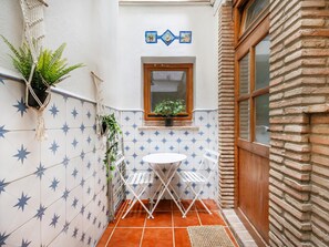 Eine kleine Terrasse mit einem weißen Tisch und Stühlen, einem Topfpflanzen und einem Fenster mit Blick.