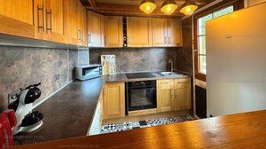 A modern kitchen with wooden cabinets, a built-in oven, a microwave, and a sink. - 4-sided Cottage 80m² near lake with garage (Matemale)