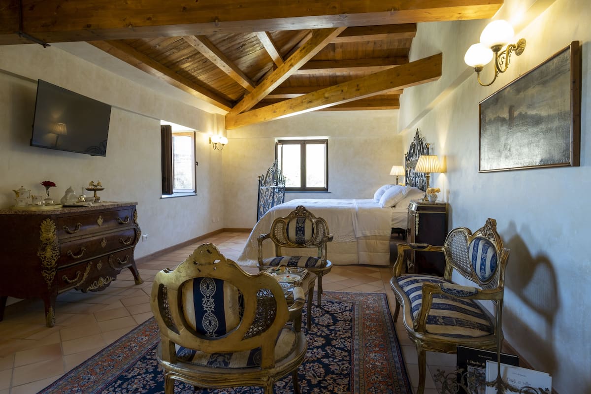 A bedroom with a bed, wooden furniture, a TV, and a painting.