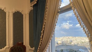 Una habitación con un ventanal grande, una silla y cortinas decorativas.