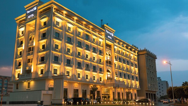 Un hotel grande de varios pisos con un cartel llamativo, varios balcones y una fachada bien iluminada.