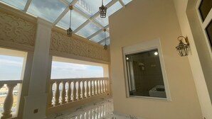 Une pièce dotée d’un plafond en verre, d’un balcon avec une balustrade et d’une fenêtre offrant une vue sur la ville.