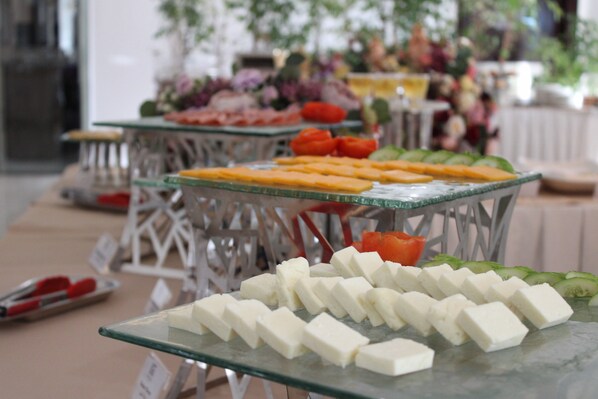 Una mesa de buffet con diversos alimentos, incluyendo queso, verduras y frutas.
