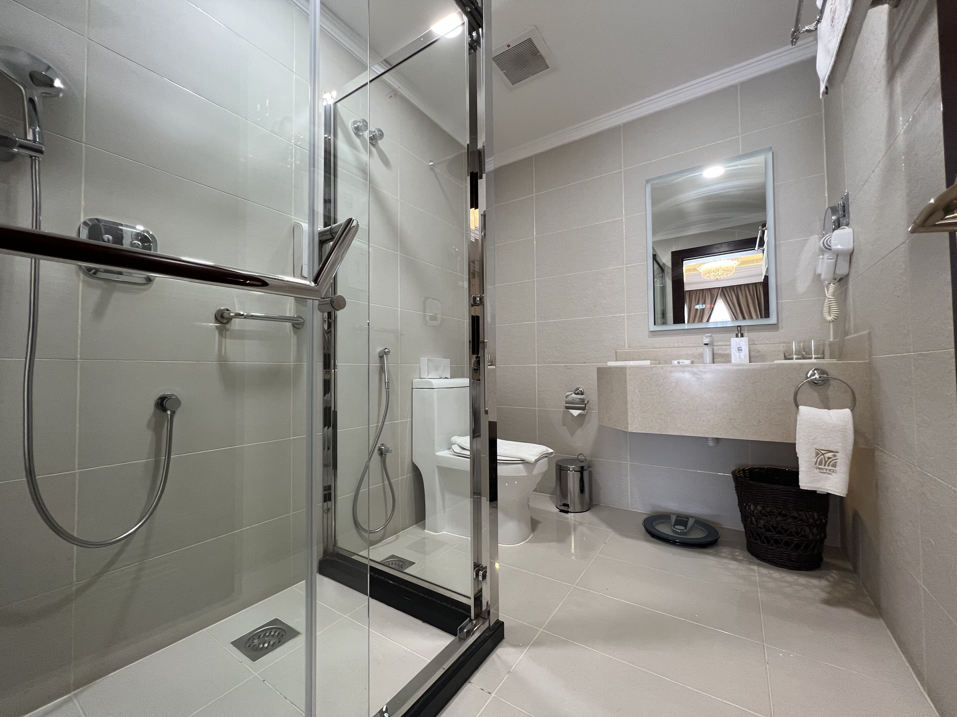 Une salle de bain moderne avec une douche à parois de verre, des toilettes et un lavabo équipé d’un porte-serviettes.
