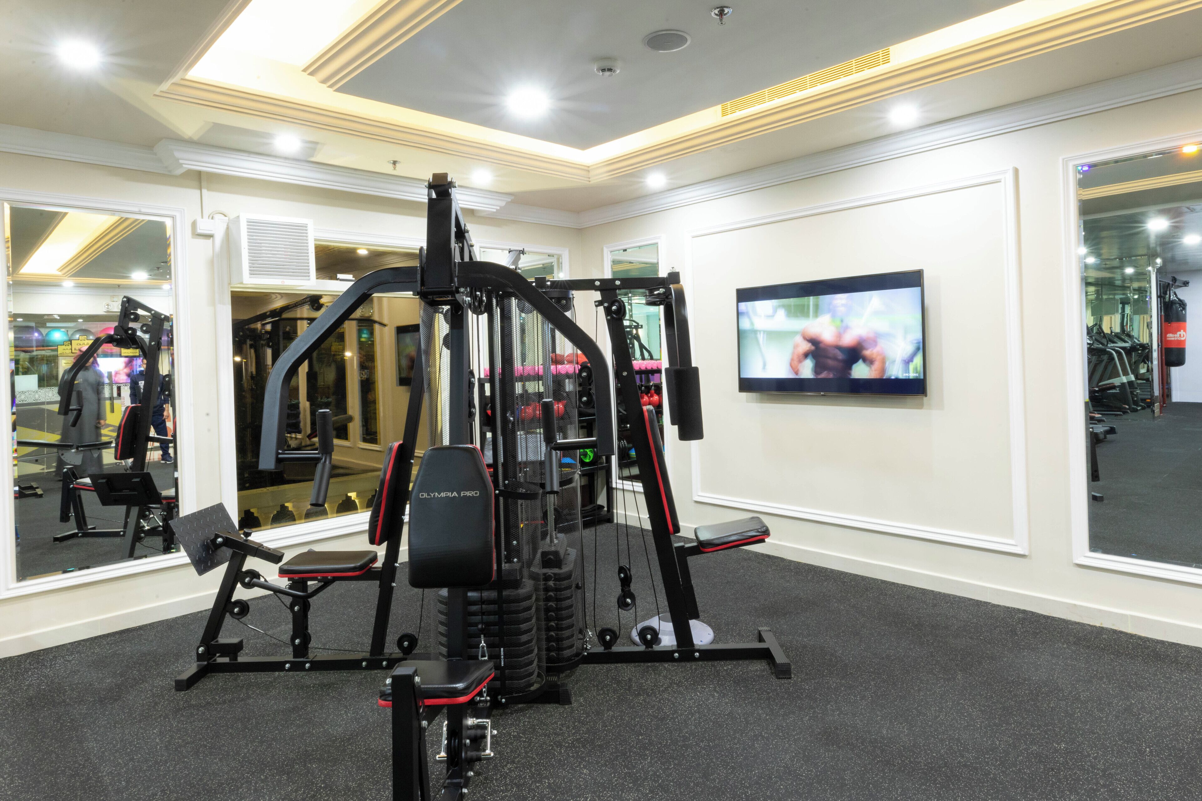 A gym with a mirrored wall, a television, and exercise equipment.