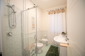Une salle de bain avec une douche à parois de verre, des toilettes et un lavabo.