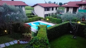 A residential area with a swimming pool surrounded by well-maintained hedges and a few trees. - Appartamento Maria Cristina (Polpenazze del Garda)