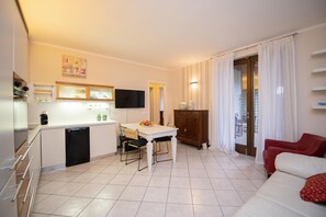 Un espace de vie compact comprenant un coin cuisine, un coin repas et une chaise rouge.