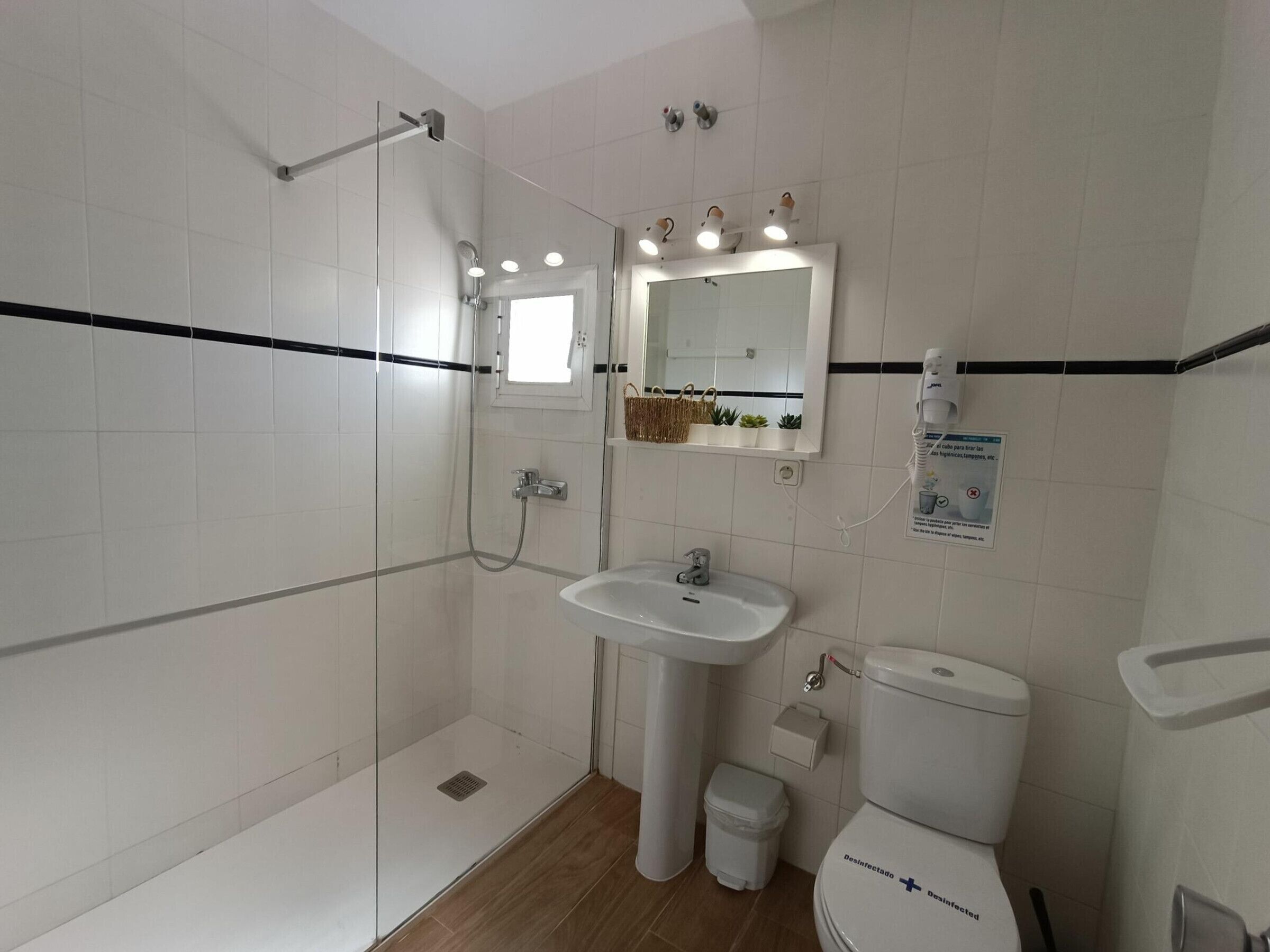 Ein modernes Badezimmer mit Duschkabine, Standwaschbecken, Toilette und einem beleuchteten Spiegel.