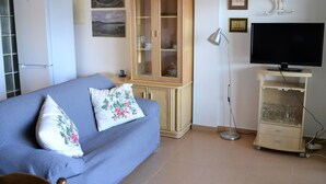 Un dormitorio con cama, armario, televisor y lámpara.