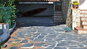 Un patio empedrado con un bote rojo, una valla verde y una planta en maceta.