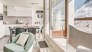 A modern interior with a dining area, a sofa, and a view of a snowy mountain. - Premium Apartment in Tignes for 6 ppl with WIFI (Tignes)