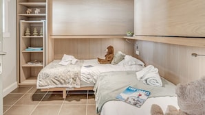 A bedroom with two beds, a wardrobe, a shelf with decorative items, and a plush toy on the bed. - Premium Apartment in Tignes for 6 ppl with WIFI (Tignes)