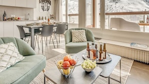 A modern interior with a dining area, seating, and a view of a snowy mountain. - Premium Apartment in Tignes for 6 ppl with WIFI (Tignes)