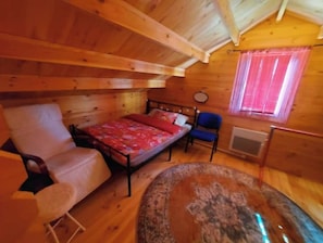 A cozy cabin room with a bed, a chair, a small table, and a window with curtains. - Pretty wooden house with large enclosed garden. (Lafage)