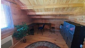 Interior de una cabaña de madera con comedor, una planta en maceta y un refrigerador empotrado.